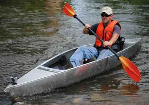Kayaker wearing life jacket navigating calm inlet